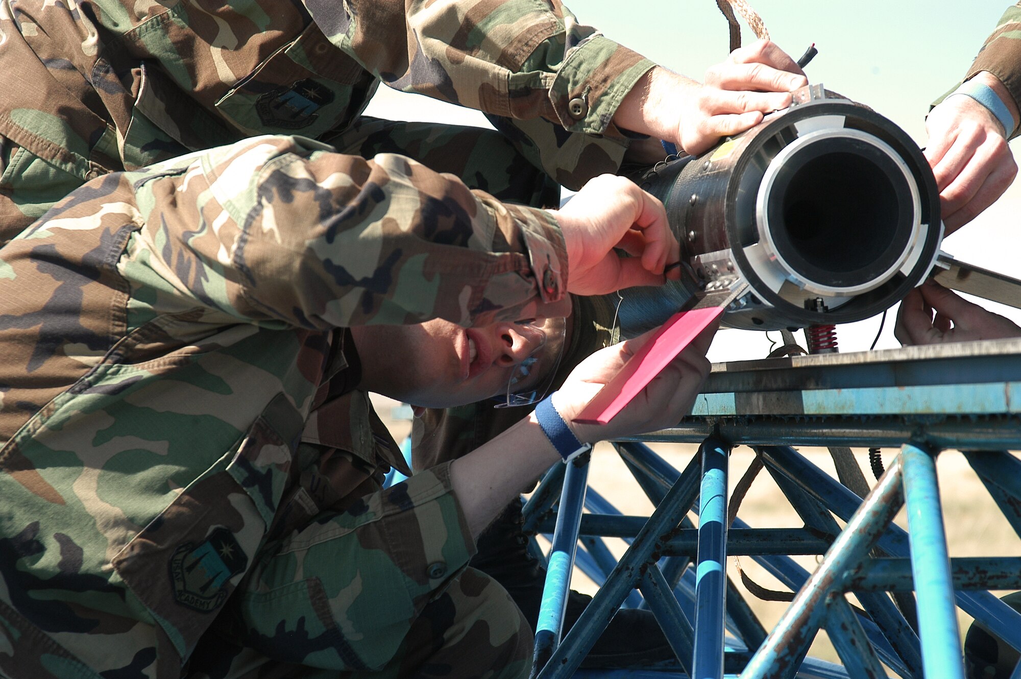 PINON CANYON MANUEVER RANGE, Colo. -- Cadet 1st Class Abraham Leigh tightens a tail fin on to the FalconLaunch rocket April 30.   During the program, cadets design, manage, build and launch a rocket as part of the Air Force Academy's Department of Astronautics course.  The program progresses each academic year, with the eventual goal of creating a rocket which can deliver a 5-pound scientific or experimental payload to an altitude of about 60 miles.  (U.S. Air Force photo by John Van Winkle)