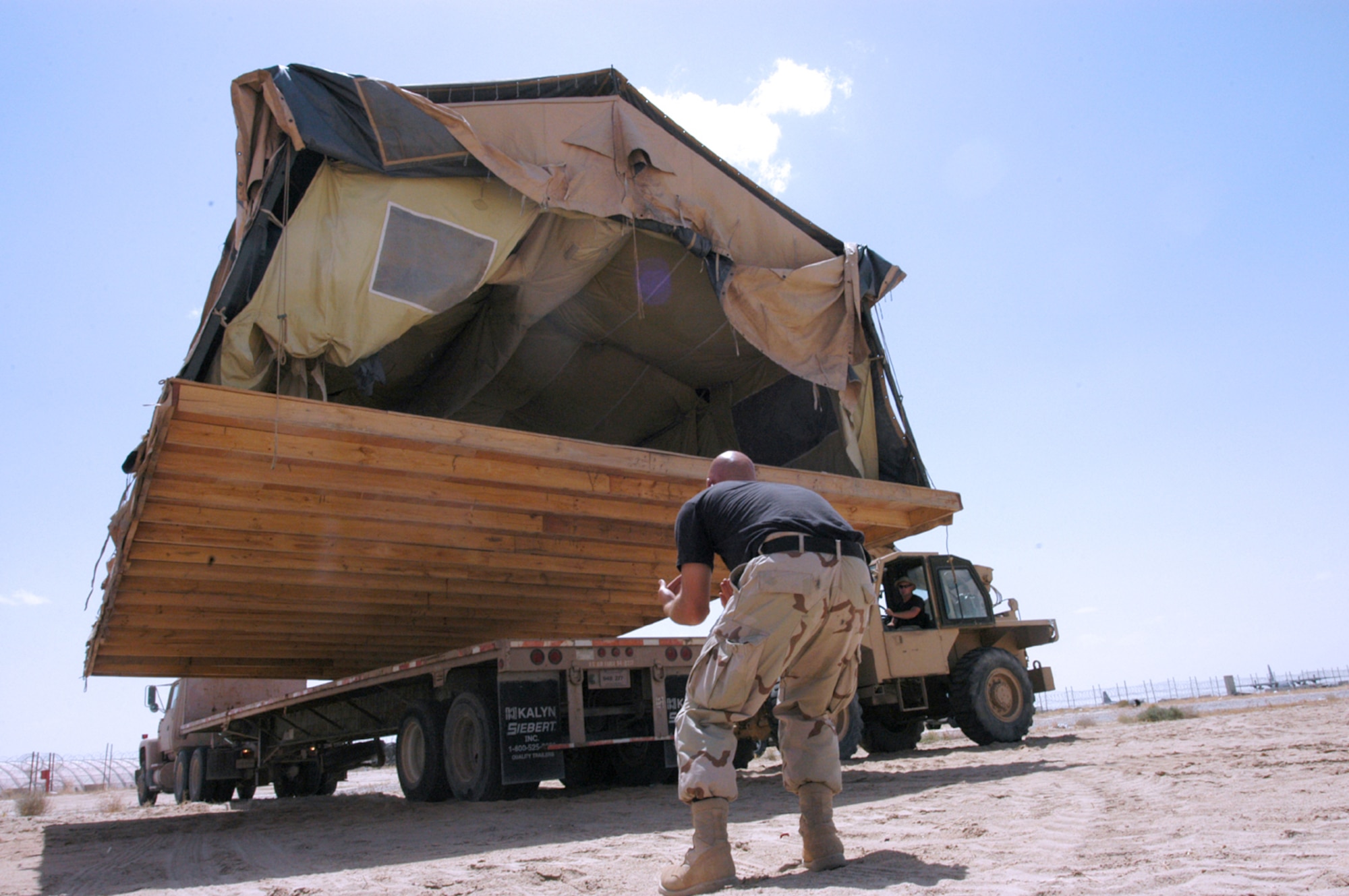 SOUTHWEST ASIA -- Staff Sgt. Aaron Carroll guides Tech. Sgt. Raymond Saunders as he uses a forklift to move a tent with its floor intact onto the back of a flatbed truck April 27.  (U.S. Air Force photo by Staff Sgt. William Farrow)