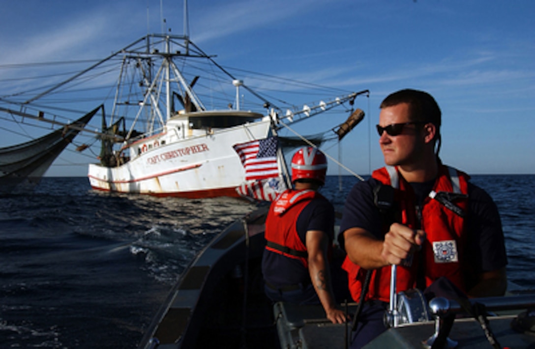 U.S. Coast Guard Petty Officer 2nd Class Karl Munson pilots a 26-foot boat while Petty Officer 2nd Class Gabriel Diaz keeps an eye on a boarding team who is inspecting a 79-foot shrimp boat in the Gulf of Mexico, off the coast of New Orleans, La., on April 27, 2005. The boarding team, from the Coast Guard Cutter Valiant, home ported in Miami, is boarding the shrimp boat to inspect for violations of federal safety and environmental regulations. 