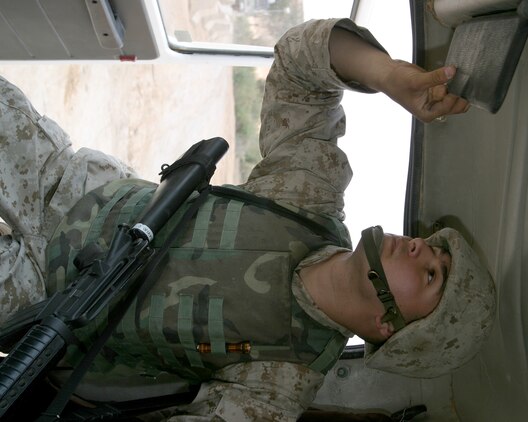 AL ASAD, Iraq--May 4, 2005, Cpl. Caesar D. Clavijo, a clarinet player with the 2nd Marine Aircraft Wing Band who is originally from Miami, Fla., searches the inside of a vehicle belonging to a local civilian before allowing it to pass into secure compound. The 2nd MAW Band performs vehicle inspections as part of their duty as a security force while forward deployed to Al Asad, Iraq.