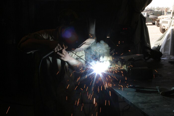 CAMP FALLUJAH, Iraq -- Lance Cpl. James Lail, a welder with Engineer Maintenance Platoon, welds together two pieces of a tongue.  Lail, a York, S.C., native, said he enjoys being busy because it helps get him through his deployment.