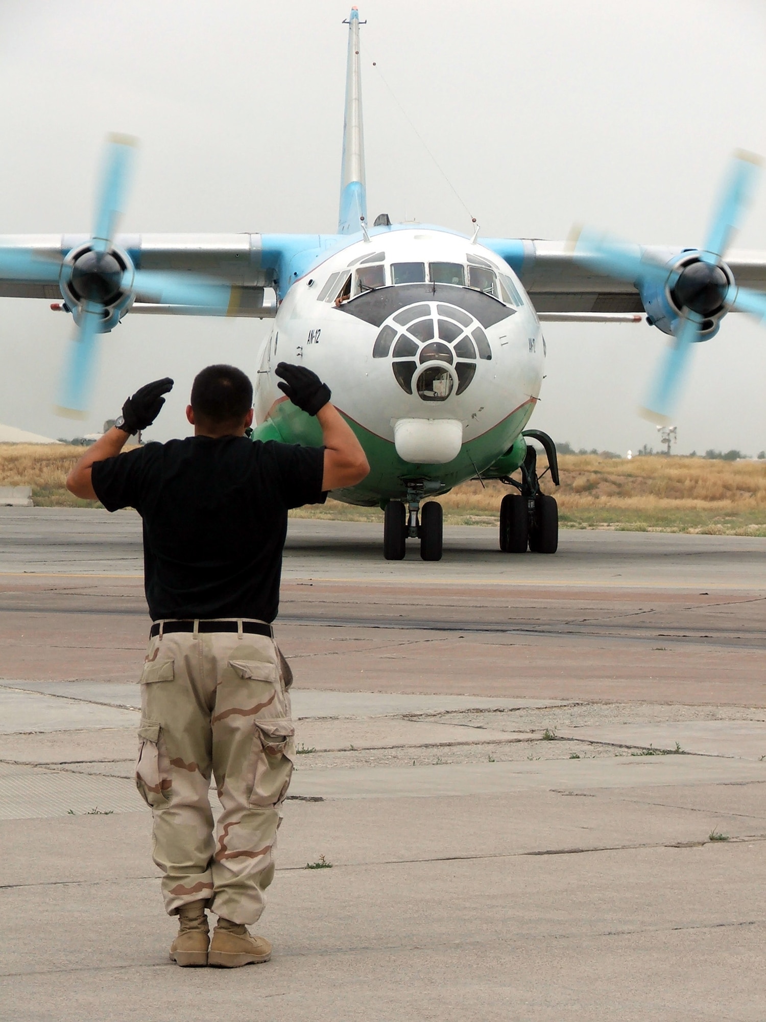 KARSHI-KHANABAD AIR BASE, Uzbekistan -- Staff Sgt. Sammy Ayala gives directions to the crew of a Russian-built AN-12 cargo plane here May 2.  He is a transient alert Airman and KC-10 Extender crew chief with the 416th Air Expeditionary Group's transient alert flight.  He is deployed from Travis Air Force Base, Calif.  (U.S. Air Force photo by Tech. Sgt. Scott T. Sturkol) 