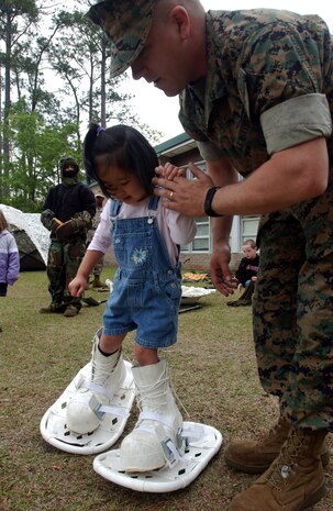 050504-M-1188A-001 CAMP LEJEUNE, N.C. (May 4, 2005) - Lance Cpl. Michael S. Rhodes assists Gabrielle Estrellado, 4, how to walk in Marine Corps issue snowshoes here May 4. More than 15 Marines with Headquarters and Service Battalion, 2nd Supply Battalion, 2nd Force Service Support Group, introduced various Marine Corps issued gear to students at the Tarawa Terrace 1 Primary School. Rhodes is a supply administration clerk for the battalion. (U.S. Marine Corps Photo by Lance Cpl. Joel Abshier)(Released)