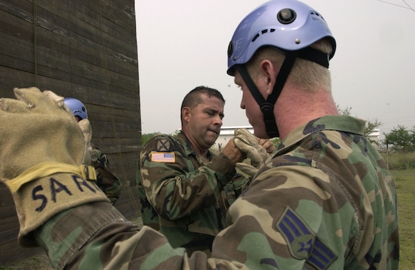 SOTO CANO AIR BASE, Honduras -- Army Master Sgt. Lorenzo Zamora helps Senior Airman Ben Roundtree prepare for a rappel training exercise here May 3.  As an additional duty, Sergeant Zamora serves as rappel master and noncommissioned officer in charge of the base's search and rescue team.  The team is Army run, but relies heavily on Airmen and Marines to accomplish their mission.  Sergeant Zamora is the Joint Task Force-Bravo Army Forces support platoon leader.  Airman Roundtree is assigned to the base fire department.  (U.S. Air Force photo by Master Sgt. Lono Kollars)