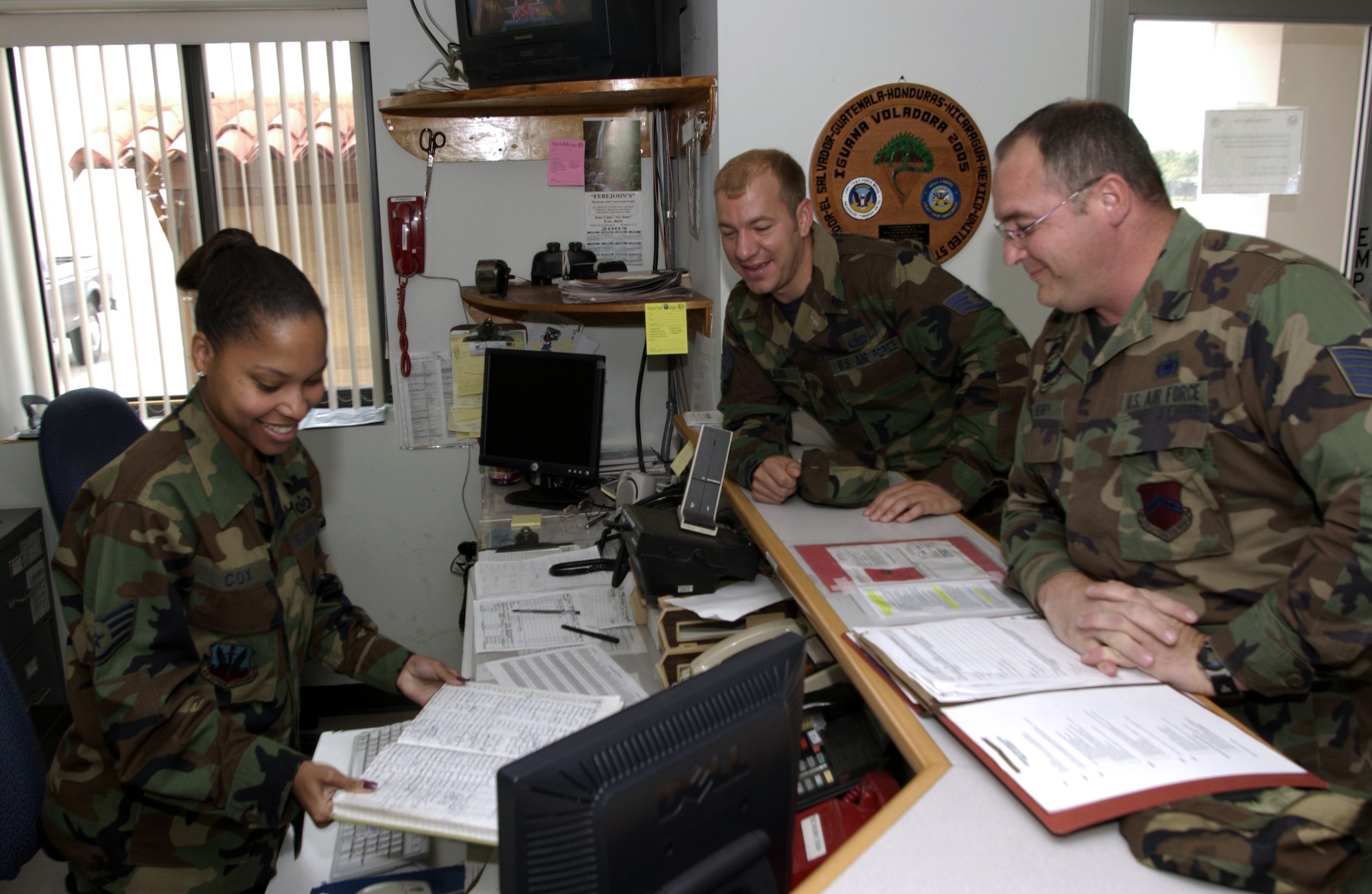 SOTO CANO AIR BASE, Honduras -- Staff Sgt. Michelle Cox processes a line badge for Tech Sgt. Marc Henry (right).  Sergeant Henry, a reservist on a 120-day deployment to the base, is replacing Staff Sgt. Charles Wilson (center) at Joint Task Force-Bravo.  Sergeant Cox is the airfield management training chief here.  (U.S. Air Force photo by Master Sgt. Lono Kollars)