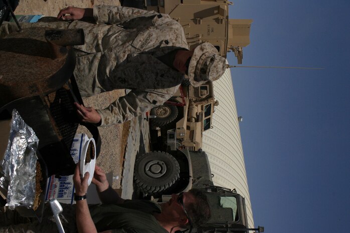 CAMP FALLUJAH, Iraq -- Gunnery Sgt. Todd Thompson, 3rd Platoon commander and Decatur, Ill., native, grills hamburgers for the Marines and Gunnery Sgt. David Clark, Infantry Weapons repair section staff noncommissioned officer and Thornville, Ohio, native, takes them to be given to the Marines. Maintenance Company, Combat Logistics Battalion 8, 2d Force Service Support Group (Forward), had a unit fun day for the Marines to "reset" the unit, giveing them a break from the normal workday.