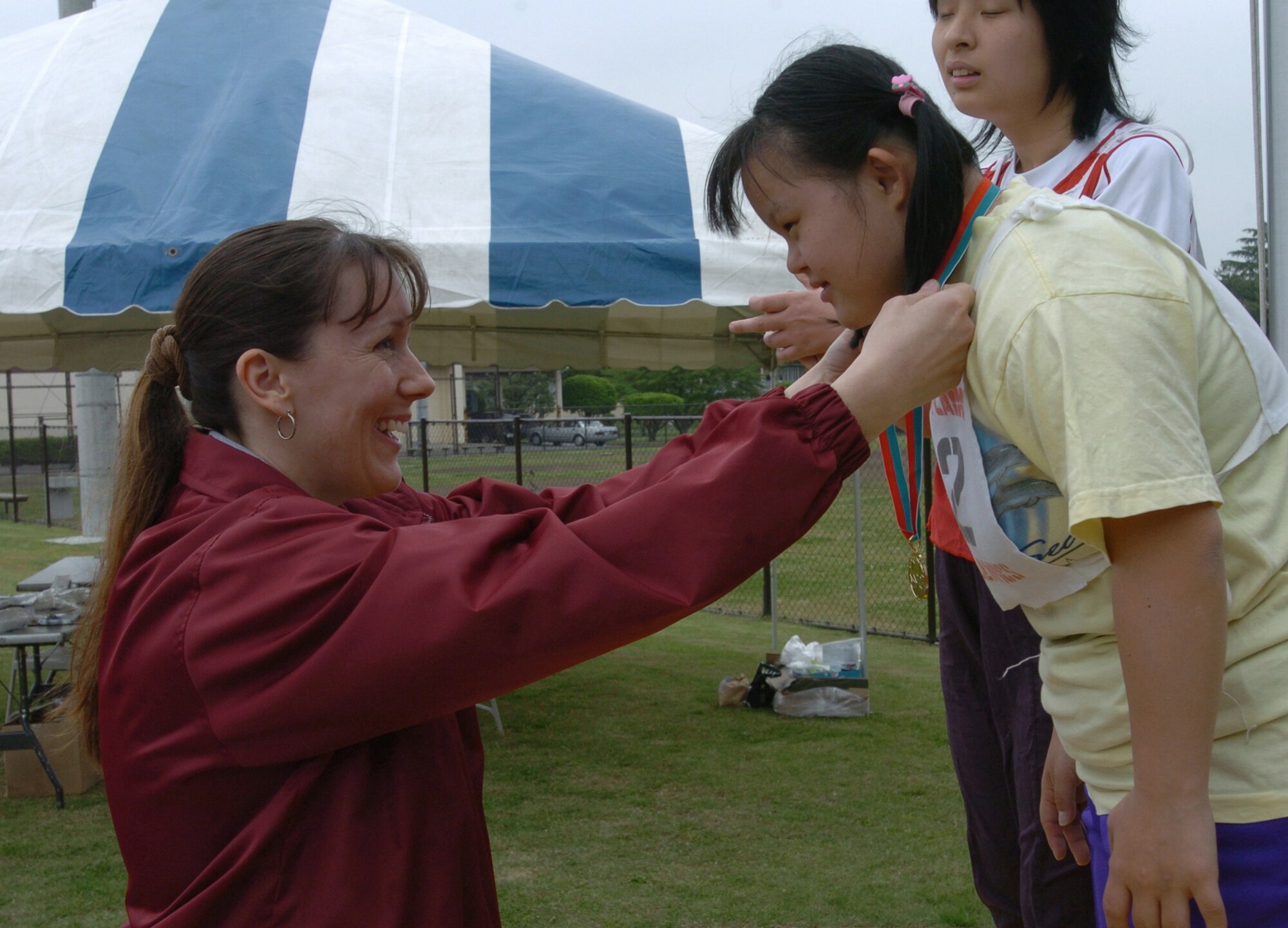 YOKOTA AIR BASE, Japan -- Tech. Sgt. Melissa Popejoy, left awards a medal to a Japanese athlete after she competed in a track and field event during the 26th Annual Kanto Plain Special Olympics here.  More than 400 athletes from 20 Japanese schools competed in the two-day event May 7 and 8, which included basketball, softball throw, swimming and bowling. Sergeant Popejoy is a cargo ramp specialist with the 730th Air Mobility Squadron.  (U.S. Air Force photo by Master Sgt. Val Gempis)