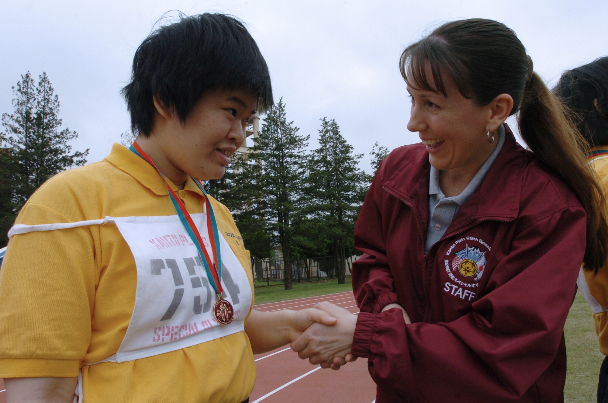 YOKOTA AIR BASE, Japan -- Tech. Sgt. Melissa Popejoy (right) shakes hands with Yuki Yano after she competed in a track and field event during the 26th Annual Kanto Plain Special Olympics here.  More than 400 athletes from 20 Japanese schools competed in the two-day event May 7 and 8, which also included basketball, softball throw, swimming and bowling.  Sergeant Popejoy is a cargo ramp specialist with the 730th Air Mobility Squadron.  (U.S. Air Force photo by Master Sgt. Val Gempis)