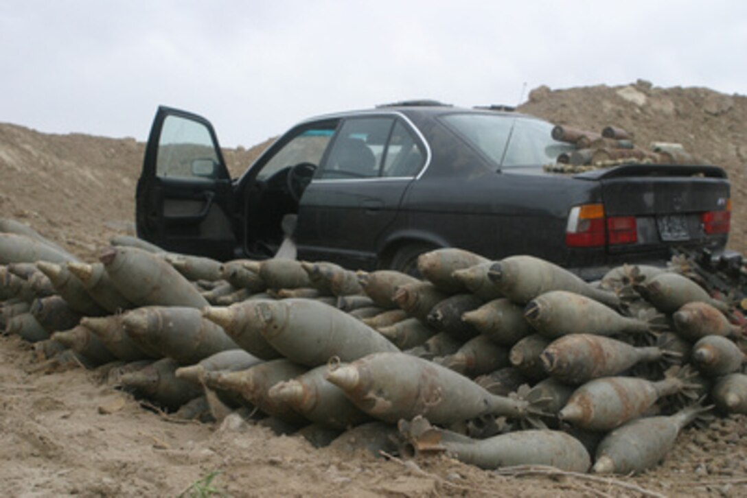 U.S. Marines examine mortar rounds and a BMW automobile in what they believe to be a car bomb in the making during security and stabilization operations in the Al Anbar Province, Iraq, on April 26, 2005. The mortars and the car are part of the 20 weapons caches that U.S. Marines from India Company, 3rd Battalion, 4th Marine Regiment found during the operations. 