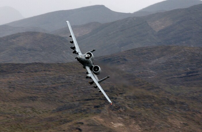 NELLIS AIR FORCE BASE, Nev. -- An A-10 Thunderbolt II maneuvers through a mountain pass during a close-air support mission May 5.  A-10s are specially designed for close-air support of ground forces.  They are simple, effective and survivable twin-engine jet aircraft that can be used against ground targets, including tanks and other armored vehicles.  This aircraft is assigned to the 66th Weapons Squadron here.  (U.S. Air Force photo by Tech. Sgt. Kevin J. Gruenwald)
