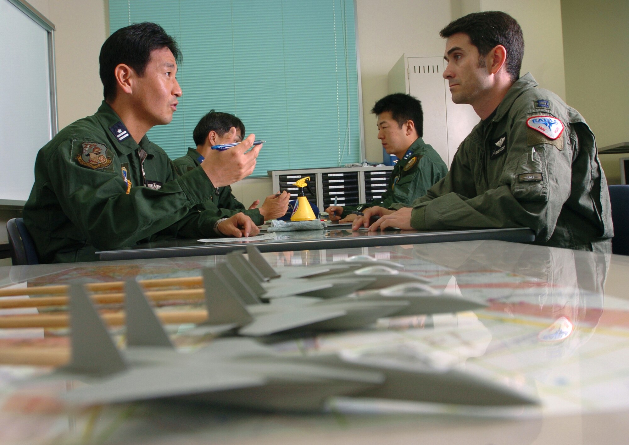 NYUTABARU AIR BASE, Japan -- Capt. Justin Fletcher (right) discusses tactics with Japanese Maj. Tagao Sugiyama before a mission.  Captain Fletcher provides F-15 Eagle pilot techniques and counterair tactics to Japanese airmen here.  He is a pilot and exchange officer assigned to the 23rd Fighter Tactical Squadron.  (U.S. Air Force photo by Master Sgt. Val Gempis)