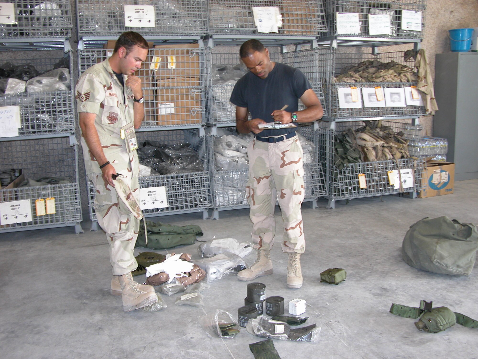 SOUTHWEST ASIA -- Staff Sgt. Cameron Marshall (left) turns in his mobility gear to Tech. Sgt. Paul Roby at a forward-deployed location.  Airmen in air and space expeditionary force cycles 3, 4, 5 and 6 can turn in their mobility bags and chemical warfare equipment to theater materiel managers before redeploying.  This equipment will be stored at the three expeditionary theater distribution centers located at primary hubs here.  Sergeant Marshall is with the Combined Air Operations Center, and Sergeant Roby is assigned to the 379th Expeditionary Logistics Readiness Squadron.  (U.S. Air Force photo by Master Sgt. Carolyn Gwathmey)