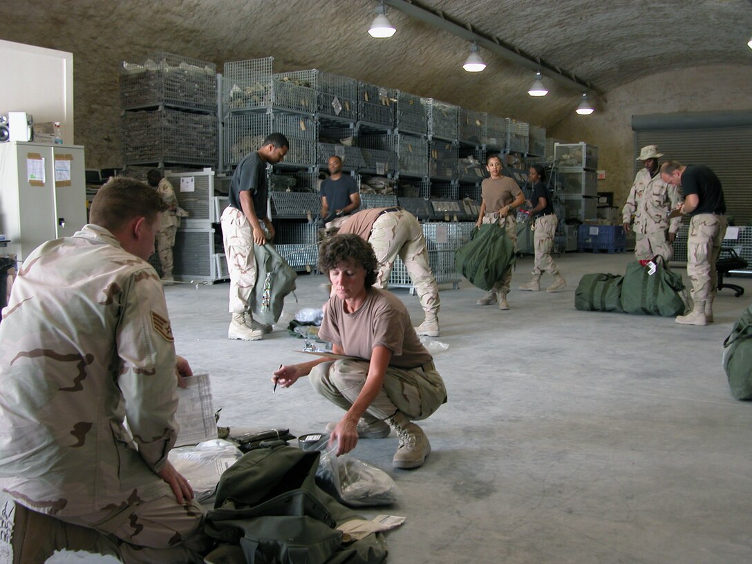 SOUTHWEST ASIA - Tech. Sgt. Marsie McClarin (right) inventories Staff Sgt. Les Whitehead's mobility gear at a forward-deployed location.  Airmen in air and space expeditionary force cycles 3, 4, 5 and 6 can turn in their mobility bags and chemical warfare equipment to theater materiel managers before redeploying.  This equipment will be stored at the three expeditionary theater distribution centers located at primary hubs here.  Sergeant McClarin is assigned to the 379th Expeditionary Logistics Readiness Squadron, and Sergeant Whitehead is assigned to the 379th Expeditionary Services Squadron.  (U.S. Air Force photo by Master Sgt. Carolyn Gwathmey)
