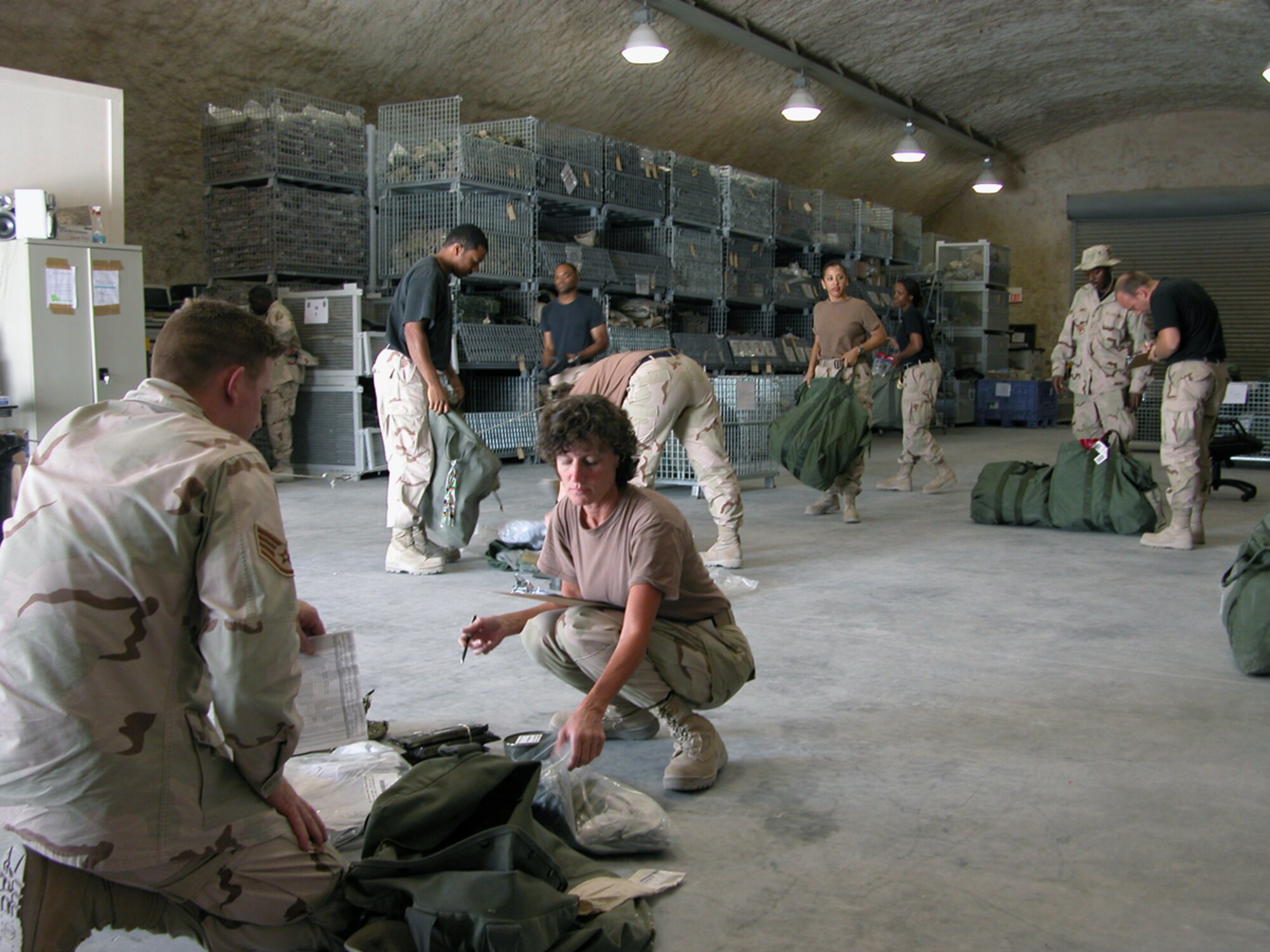 SOUTHWEST ASIA - Tech. Sgt. Marsie McClarin (right) inventories Staff Sgt. Les Whitehead's mobility gear at a forward-deployed location.  Airmen in air and space expeditionary force cycles 3, 4, 5 and 6 can turn in their mobility bags and chemical warfare equipment to theater materiel managers before redeploying.  This equipment will be stored at the three expeditionary theater distribution centers located at primary hubs here.  Sergeant McClarin is assigned to the 379th Expeditionary Logistics Readiness Squadron, and Sergeant Whitehead is assigned to the 379th Expeditionary Services Squadron.  (U.S. Air Force photo by Master Sgt. Carolyn Gwathmey)
