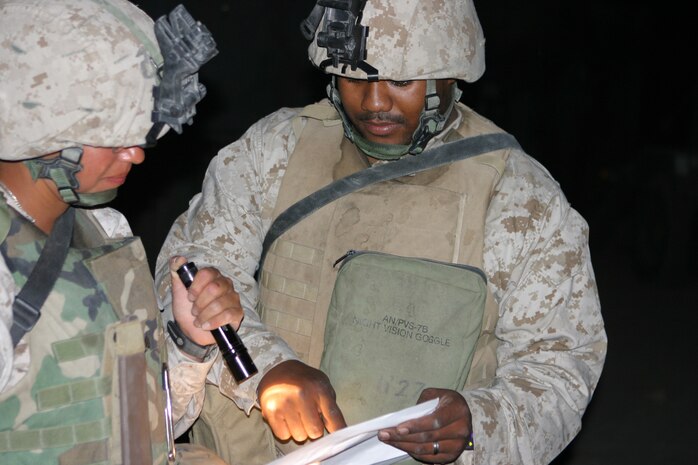 CAMP TAQADDUM, Iraq - Sergeant Angelina S. Arellano (left), a San Diego native, and Lance Cpl. James R. Milton, a Greensboro, N.C., native, with the Marine Air Ground Task Force Distribution Center, Supply Detachment, Combat Logistics Regiment 25, 2d Force Service Support Group (Forward) here, go over the paperwork during a delivery May 13. They are two of the five Marines responsible for tracking all the gear and cargo for the convoys leaving Camp Taqaddum.