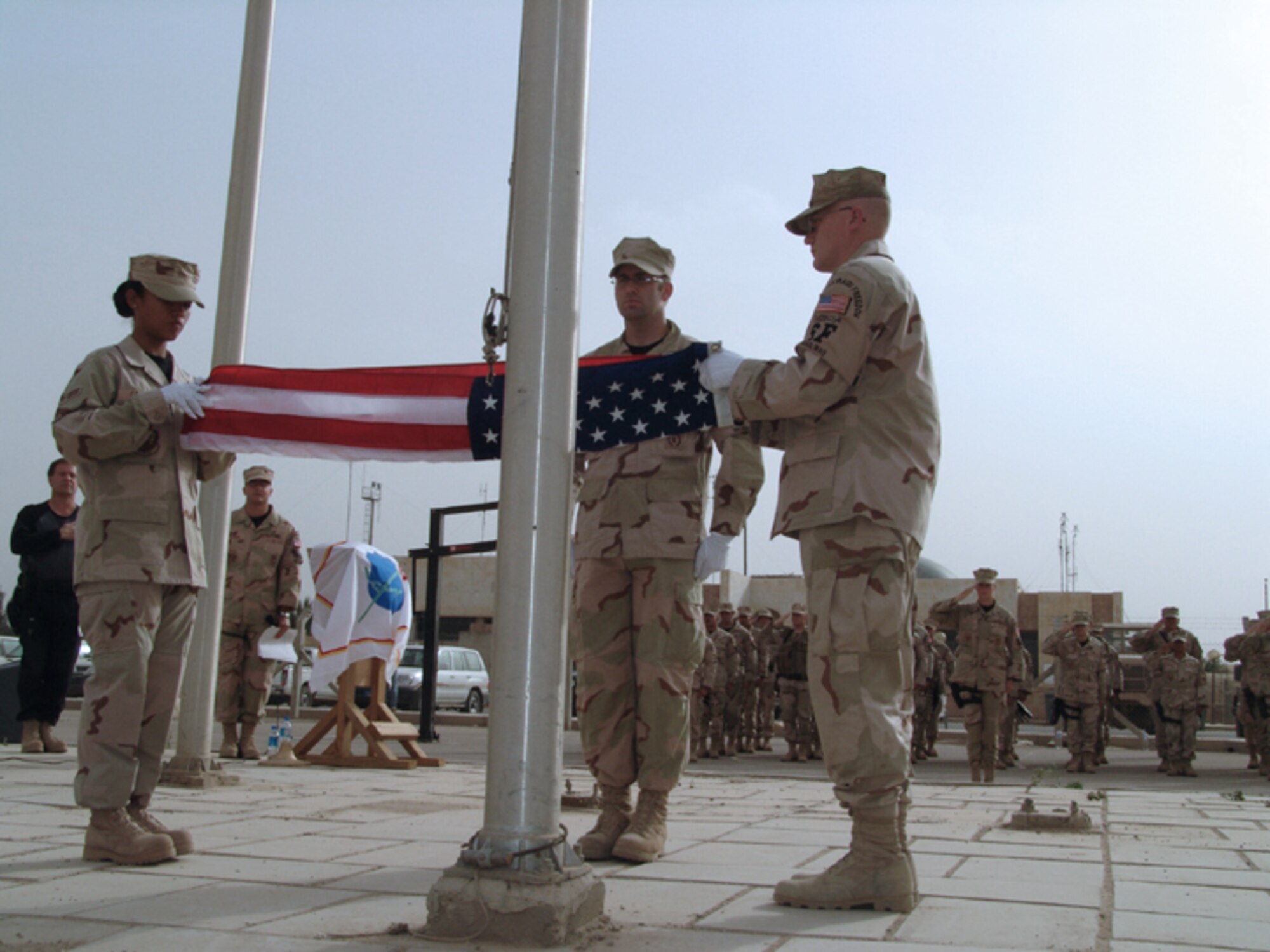 BAGHDAD, Iraq - (From left) Airman 1st Class Ann Rachel Cajulis and Staff Sgts. Steven Callahan and Richard Dodson fold the flag in tribute to fallen security forces comrades during a ceremony here May 13 observing Peace Officers Memorial Day.  The flag will be presented to the family of an Atlantic City police officer who was recently killed in the line of duty.  The Airmen are assigned to the 447th Air Expeditionary Group's security forces flight.  Airman Cajulis and Sergeant Callahan are deployed from Cannon Air Force Base, N.M., and Sergeant Dodson is deployed from Vance AFB, Okla.  (U.S. Air Force photo by Tech. Sgt. Brian Davidson)