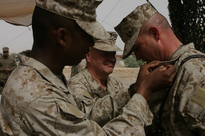 CAMP TAQADDUM, Iraq (May 18, 2005) – Brigadier Gen. John E. Wissler, commander of 2d Force Service Support Group (Forward) and Brooklyn Park, Minn., native, has Pfc. Jamond D. Roberts, a Cheneyville, La., native, and Lt. Cmdr. Timothy D. Hogan, Combat Logistics Regiment 25, chaplain and Southgate, Mich., native, pin his stars on his collar during his frocking ceremony here May 18. “I get to serve with the best that America has to offer, and they are represented by Pfc. Roberts,” said Wissler. “The youth of America committed to our nation in a time of war as United States Marines. I would like to say thank you to every Marine I’ve ever served with.  Every one of them has a little piece of this promotion today.” (Photo by Sgt. Kristin S. Jochums)