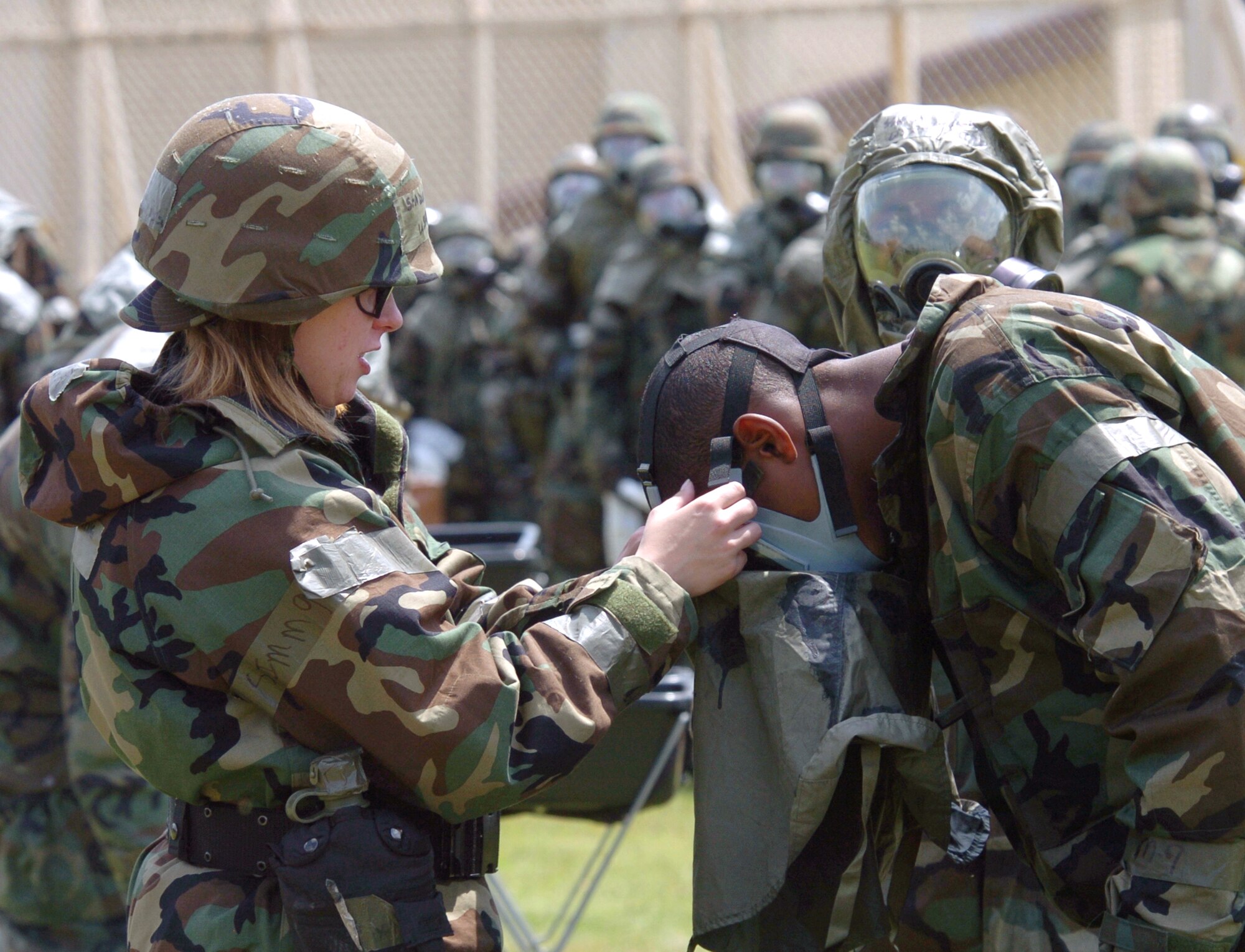 YOKOTA AIR BASE, Japan -- Senior Airman Danielle Ring (left) helps an Airman with his gas mask at the contaminated control area during "ability to survive and operate" training here.  Airman Ring helped students understand step-by-step decontamination procedures.  She is a readiness flight instructor with the 374th Civil Engineer Squadron.  (U.S. Air Force photo by Master Sgt. Val Gempis)