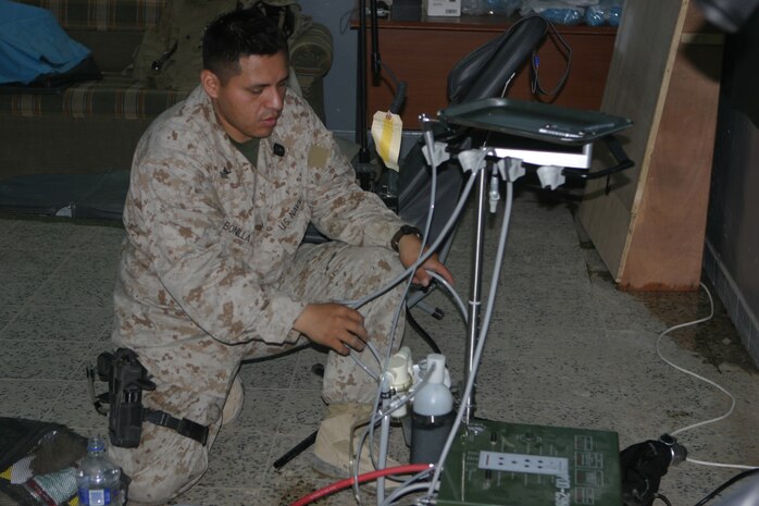 CAMP TAQADDUM, Iraq (May 23, 2005) -  Petty Officer 2nd Class Luis Bonilla, a dental equipment repair technician with Headquarters and Service Battalion, 2d Force Service Support Group (Forward), prepares a Dental Equipment Field Treatment Operating System during a humanitarian assistance mission in Habbaniyah May 20. The Miami native was part of a three-man team treating Iraqi Intervention Force soldiers who complained of pain and needed teeth surgically removed. (Photo by Cpl. John E. Lawson Jr.)