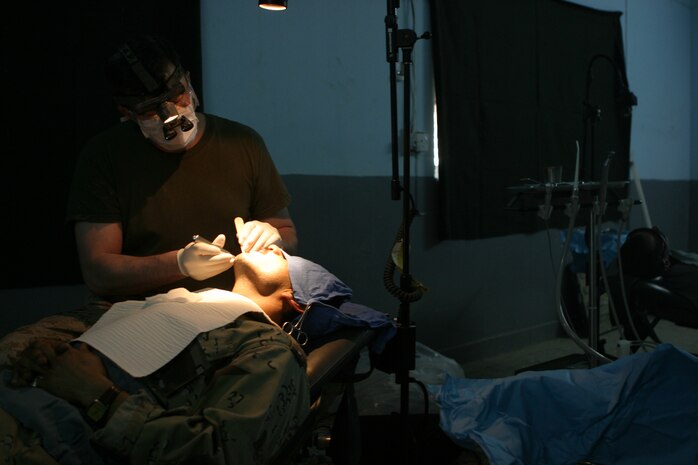 CAMP TAQADDUM, Iraq (May 23, 2005) -  Commander William Davidson, doctor of dental surgery and dental platoon commander with Headquarters and Service Battalion, 2d Force Service Support Group (Forward) performs dental surgery on an Iraqi Intervention Force soldier during a humanitarian assistance mission in Habbaniyah May 20. The Littlefield, Texas, native, along with a two other Sailors, treated 33 patients and removed 63 teeth, mostly half-decayed, from soldiers who had previously complained of pain during this two-day mission. (Photo by Cpl. John E. Lawson Jr.)