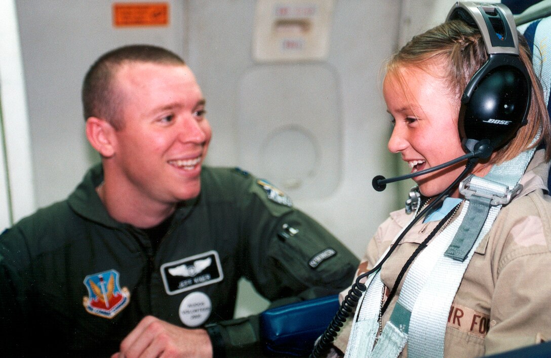 TINKER AIR FORCE BASE, Okla. -- Checking out communications aboard an E-3 Sentry here, 9-year-old Erin Trace is assisted by Capt. Jeff Kiger.  The aircraft tour was part of deployment activities 150 children had the opportunity to experience May 14 during Operation Kids Understanding Deployment Operations.  Captain Kiger is assigned to the 960th Airborne Air Control Squadron.  (U.S. Air Force photo by Kirk McPheeters)