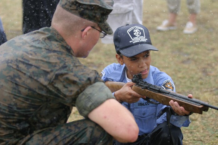 Sgt. Clinton Schwarz, primary marksmanship instructor, coaches U.S. Navy League Cadet Luis Abreu through his kneeling course of fire. Though the rain began to fall, Abreu and the other cadets were not inclined to put any of the training on hold.