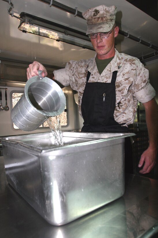 Cpl. Carl Cornett, warehouse clerk with 2nd Battalion, 9th Marine Regiment, 2nd Marine Division, II Marine Expeditionary Force, adds water to a pan of food during the Maj. Gen. W. P. T. Hill Memorial Award for Food Service competition here Oct. 17. The judges evaluated the field mess on multiple levels including site preparation, security, food preparation and presentation.