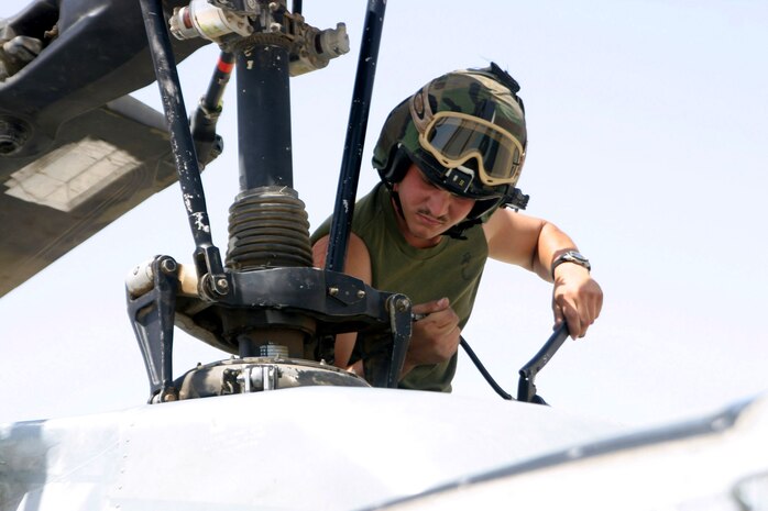AL TAQADDUM, Iraq - Lance Cpl. Kevin Cota, a crew chief with Marine Light/ Attack Squadron 775 greases the rotor of a UH-1N here May 22. Cota and the Coyotes are working hard to support casualty evacuations and ground Marines throughout Iraq.