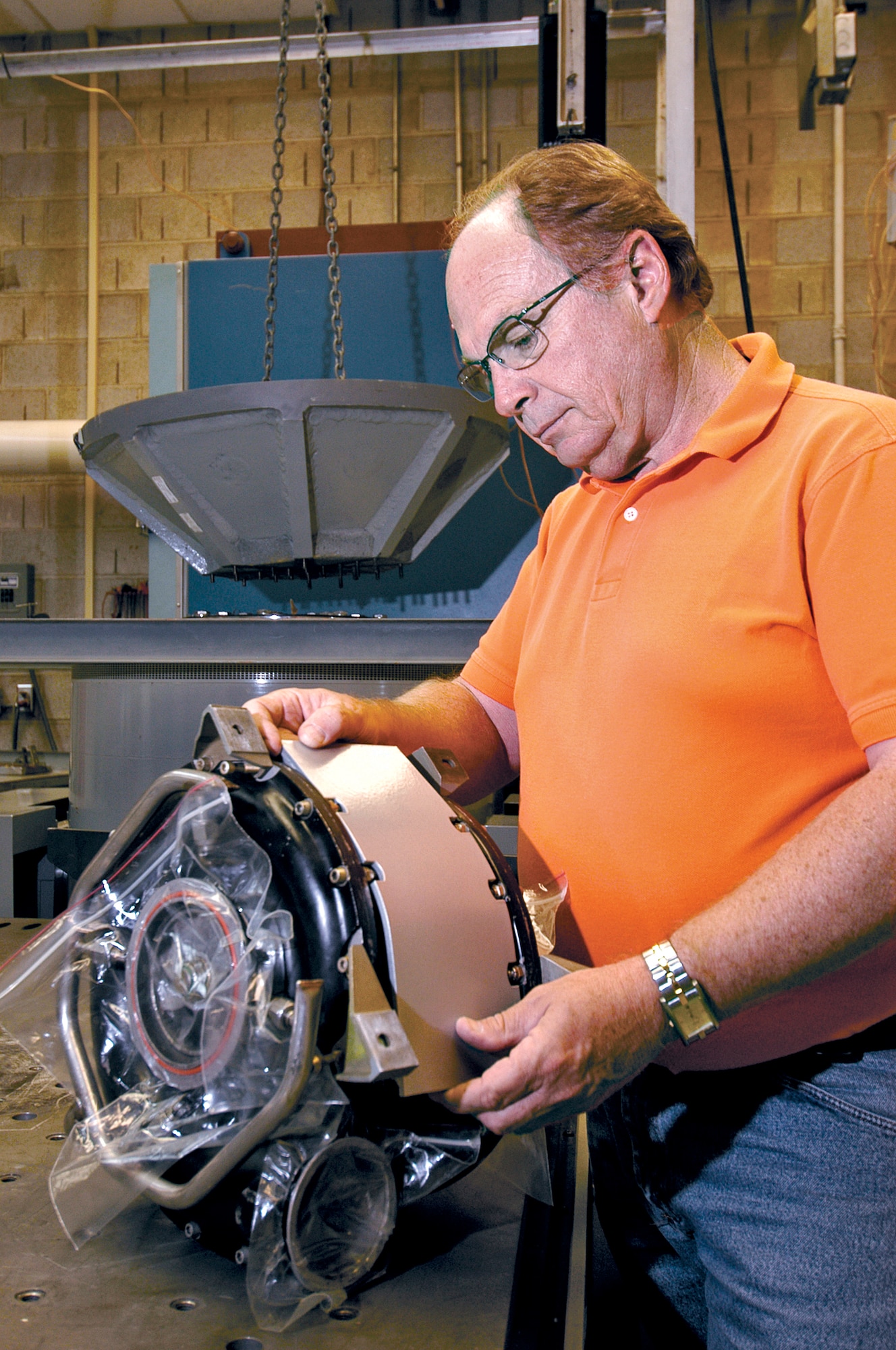 TINKER AIR FORCE BASE, Okla. -- Bill Fleenor examines a KC-135 Stratotanker air cycle machine with a new metal scatter shield that he will test in the vibration test facility here where he works as a mechanical engineer.  Once attached to a specially made mount, the part will be subjected to extreme vibration conditions similar to those during flight.  (U.S. Air Force photo by Margo Wright)