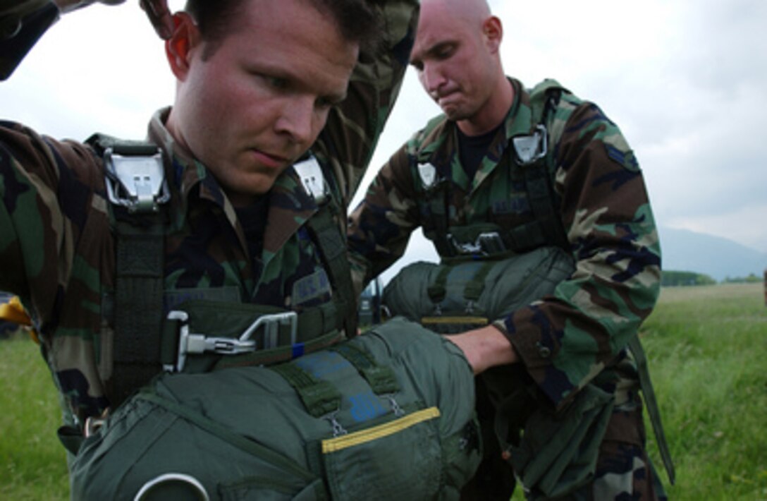 Air Force Airman 1st Class Jeff Chairimonte attaches a reserve parachute to Capt. Matt Baugh at Aviano Air Base, Italy, in preparation for a parachute jump with soldiers from the Army's 173rd Airborne Brigade over Maniago, Italy, on May 19, 2005. Chairimonte and Baugh are attached to Tactical Air Control Party, Detachment 1, 4th Air Support Operations Group, Heidelberg, Germany. 