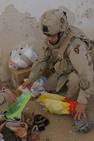 CAMP TAQADDUM, Iraq (May 28, 2005) - Specialist Jason E. Sternberg, a 33-year-old Lewisville, Texas native, sets out shoes for the residents of Al Kabani to choose from. During a visit to the village May 25, the Soldiers with 3rd platoon, Alpha Company, 2nd Battalion, 112th Armor, 36th Infantry Division, distributed more than 225 pairs of shoes to the families in need.
