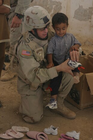 CAMP TAQADDUM, Iraq (May 28, 2005) - Specialist Jason E. Sternberg, a 33-year-old Lewisville, Texas native, helps an Iraqi child find a pair of shoes during a civil affairs mission May 25.  During a visit to the village May 25, the Soldiers with 3rd platoon, Alpha Company, 2nd Battalion, 112th Armor, 36th Infantry Division, distributed more than 225 pairs of shoes to the families in need.