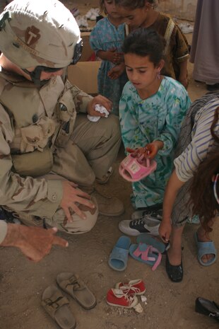 CAMP TAQADDUM, Iraq (May 28, 2005) - An Iraqi girl picks out a pair shoes May 25, with the help of a Soldier. During a visit to the village May 25, the Soldiers with 3rd platoon, Alpha Company, 2nd Battalion, 112th Armor, 36th Infantry Division, distributed more than 225 pairs of shoes to the families in need.