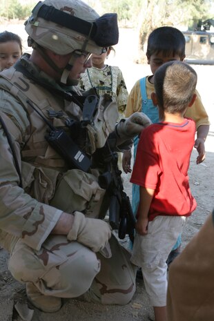 CAMP TAQADDUM, Iraq (May 28, 2005) - A Soldier takes a minute to kneel down and talk with an Iraqi boy during a civil affairs mission in Al Kabani.  The Soldiers with 3rd platoon, Alpha Company, 2nd Battalion, 112th Armor, 36th Infantry Division, came to the village to distribute more than 225 pairs of shoes to the families in need.