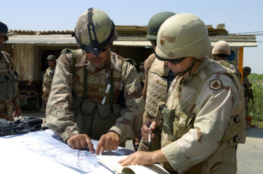 An Iraqi soldier with the 3rd Brigade, 5th Iraqi Army, and U.S. Army Maj. Davis of the 18th Airborne Corps Military Transition Team review a map of the area during operations in Wasit Province, Iraq, on May 20, 2005. 