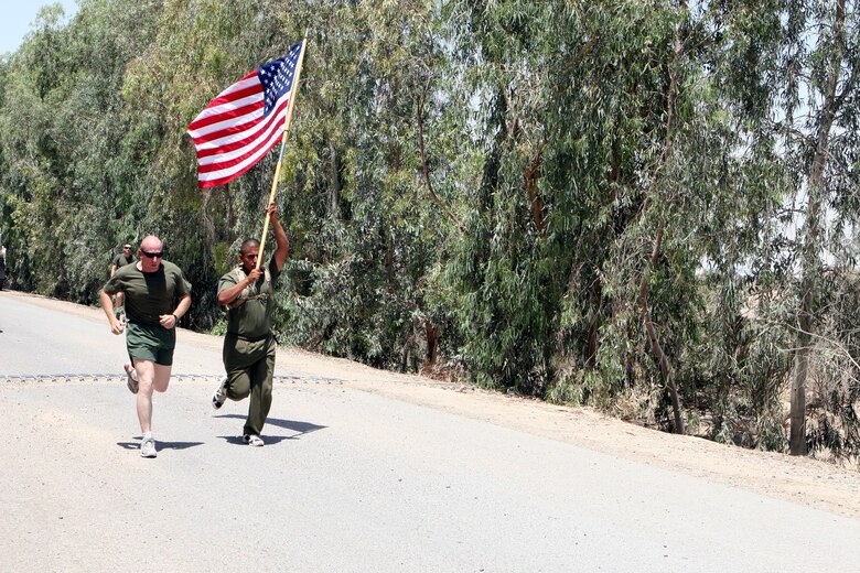 After a Marine detail rendered honors, Combat Center Marines salute during the playing of Taps on Memorial Day (background). More than 100 people attended the ceremony on May 30 at the Twentynine Palms Cemetery.
