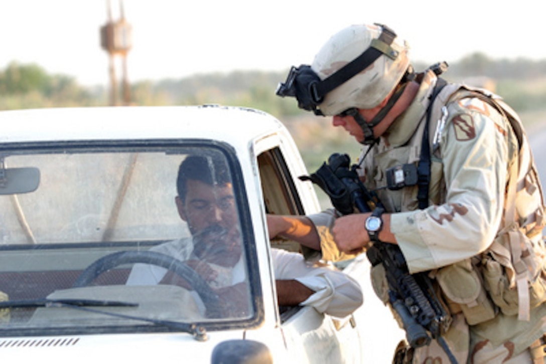 U.S. Army Sgt. Todd Owen inspects an Iraqi citizen's identification at a vehicle checkpoint in Hasawa, Iraq, on May 26, 2005. Owen and his fellow soldiers of the 155th Brigade Combat Team, 98th Calvary Regiment are searching vehicles for weapons, ammunition and questioning locals about insurgent activity. 