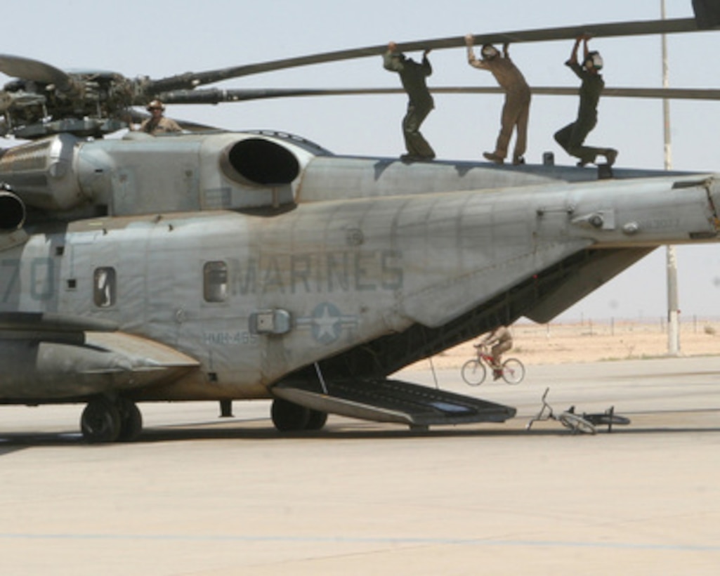 Three Marines perform a balancing act as they lift a rotor blade of a CH-53 Super Stallion during maintenance on the aircraft at Al Asad, Iraq, on May 21, 2005. The Marines are attached to Marine Heavy Helicopter Squadron 465 deployed from Marine Corps Air Station Miramar, Calif. 