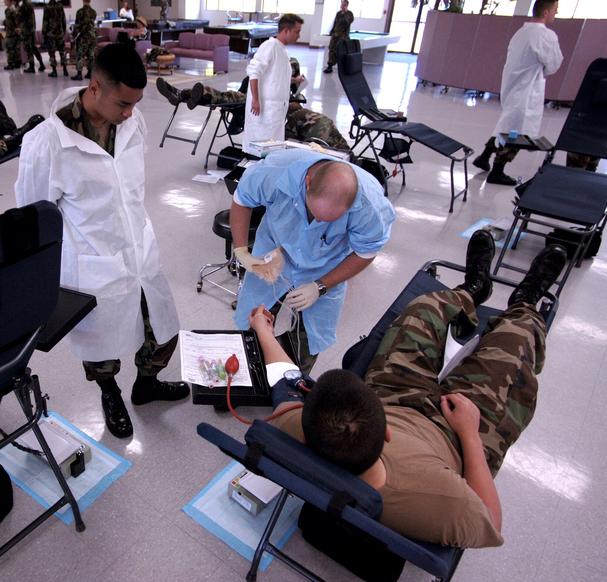 HICKAM AIR FORCE BASE, Hawaii (AFPN) -- Spc. Andrew Harris (center) and Pfc. Jonah Lantaya (left), prepare Senior Airman Christopher Wnuk (right) to give blood.  The base conducted a base wide blood drive at the Hickam Community Activity Center Oct. 27. Specialist Harris is a medical lab technician from Alpha Company, Tripler Army Medical Center.  Private Lantaya is a student in training and Airman Wnuk is assigned to the15th Civil Engineering Squadron here. (U.S. Air Force photo by Tech. Sgt. Shane A. Cuomo) 
