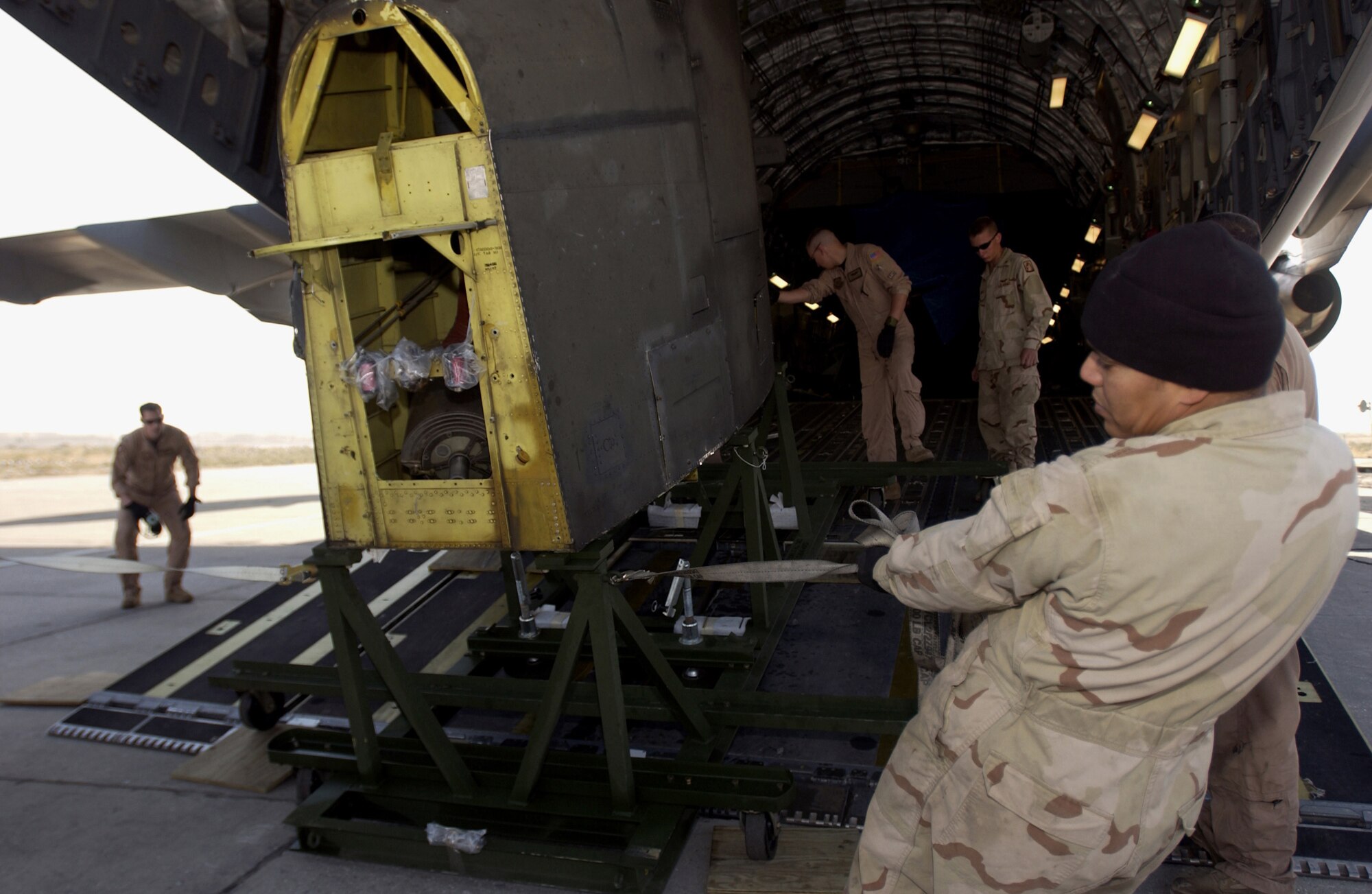 U.S. Army Soldiers from Fort Sill, Okla., and U.S. Air Force loadmasters from of McCord Air Force Base, Wash., work together to unload disassembled CH-47D helicopter parts from a C-17 Globemaster III at Bagram Airfield, Afghanistan, Oct. 21, 2005.  The helicopters are being reassembled and forward deployed to Pakistan. Department of Defense is delivering disaster relief supplies and services as part of a multinational effort to provide aid and support to Pakistan and parts of India and Afghanistan following a devastating earthquake. (U.S. Air Force photo by Staff Sgt. Ashley S. Brokop) (Released)
