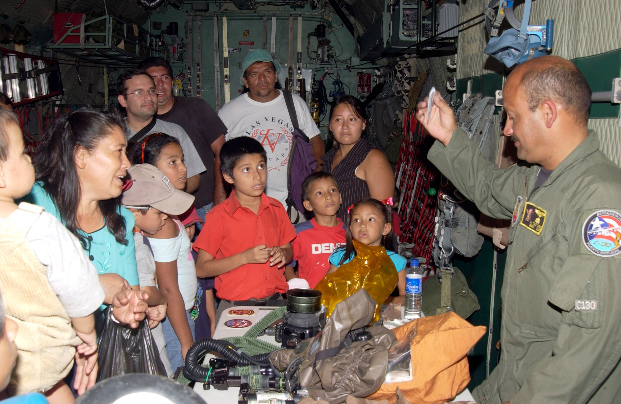 ILOPANGO AIR BASE, El Salvador (AFPN) -- Master Sgt. Alberdecton Cruz, a Puerto Rican Air National Guard loadmaster, displays aircrew equipment to El Salvadorians during an air show in San Salvador. The PR ANG C-130 Hercules was the only U.S. aircraft on static display during the Ilopango Air Show 2005. Other U.S. Air Force participants included 150 Airmen, the F-15 West Coast Demonstration Team from Eglin Air Force Base, Fla.; the U.S. Air Force Thunderbirds from Nellis AFB, Nev.; a New Hampshire ANG KC-135 Stratotanker and two C-17 Globemaster IIIs from McChord AFB, Wa. and McGuire AFB, N.J. (U.S. Air Force photo by Staff Sgt. Matthew Lohr) 