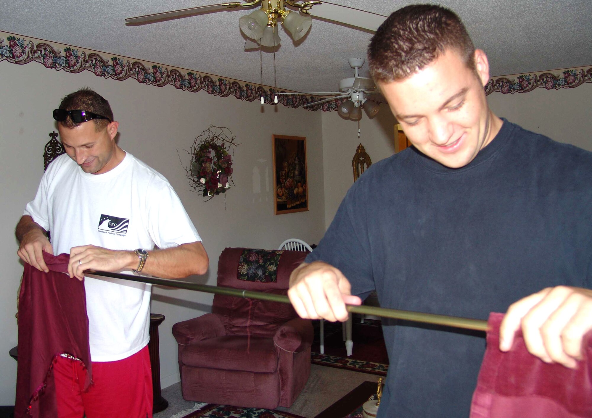 SHALIMAR, Fla. (AFPN) -- First Lt. Don Gray (left) and Senior Airman Paul Waldrep hang curtains in Jackie Robertson's home at the Bob Hope Village here, during Make A Difference Day. Lieutenant Gray is a 46th Maintenance Group quality assurance officer in charge, and Airman Waldrep is a 96th Civil Engineer Squadron firefighter. (U.S. Air Force photo by Lois Walsh) 