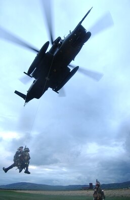 Senior Airmen Christopher Freeman and Robert Gutierrez, 321st Special Tactics Squadron, pararescueman and combat controller respectively practice alternate extraction tactics dangling from the MH-53M Pave Low IV's hoist and cable during the 352nd Special Operation Group's Operational Readiness Inspection held at RAF Machrihanish in Scotland as Tech. Sgt. Jason Lydon, 321st STS, pararescue team leader ensures the two-man team operate safely. The device used to hoist two men quickly out of harms way was developed by airmen serving during the Vietnam conflict.    