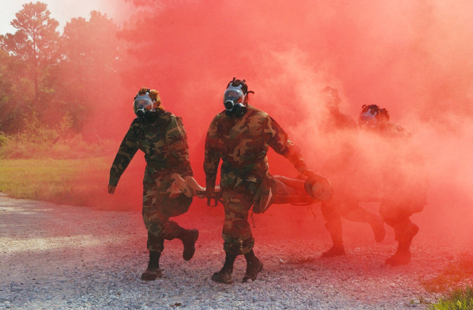 TYNDALL AIR FORCE BASE, Fla. (AFPN) -- Capt. Karen Kramer, left, and Staff Sgt. Jamilah Nailor help carry a litter with a 150-pound mannequin through an obstacle course Oct. 14. The red smoke acted as a chemical agent explosion, and the Airmen had to quickly don their gas masks and get the "downed pilot" to safety. (U.S. Air Force photo by 2nd Lt. William Powell)
