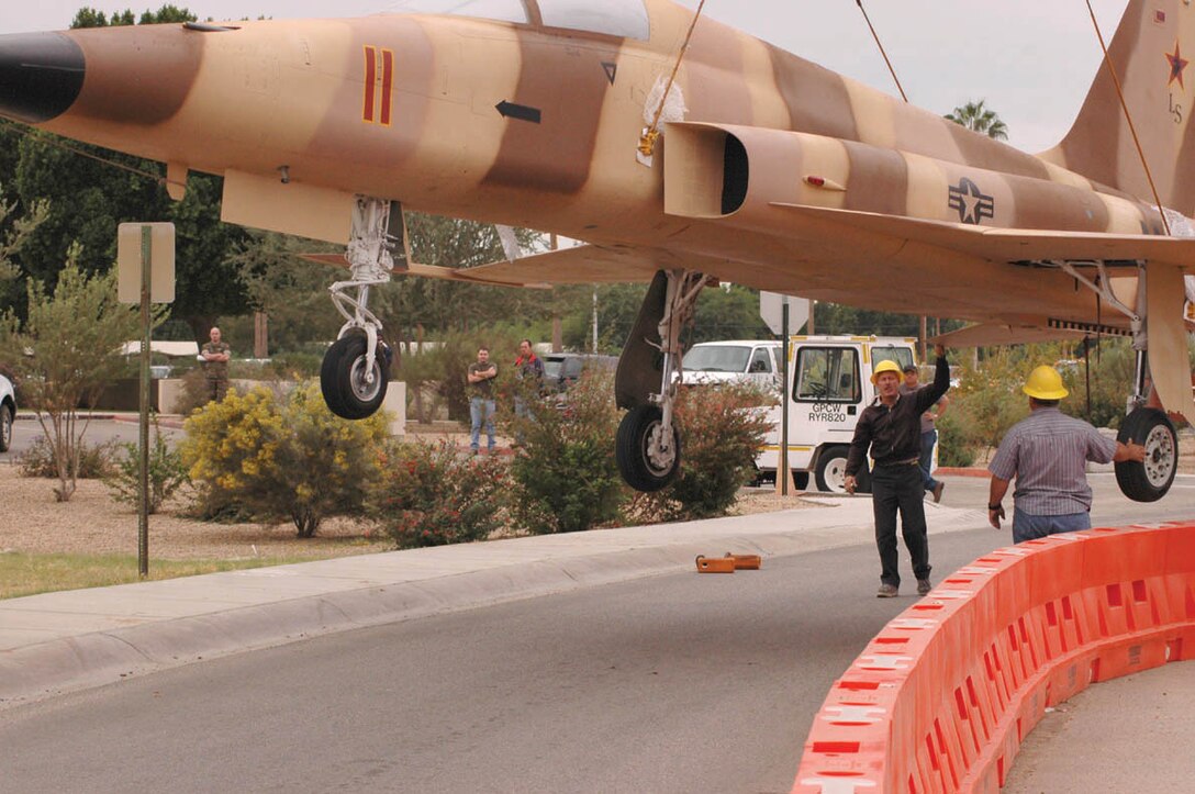 Sikorsky Support Systems Inc. guide an F-5E Tiger as it is lifted by a crane over the concrete barriers next to the main gate here Nov. 3. Onlookers included representatives from Sikorsky and Marine Fighter Training Squadron 401, and was called by some ?the slowest F-5 in the air.? The F-5E was put on display as a joint project by the Marine Corps and Sikorsky to honor the work done by the Marines and civilians of Marine Fighter Training Squadron 401.