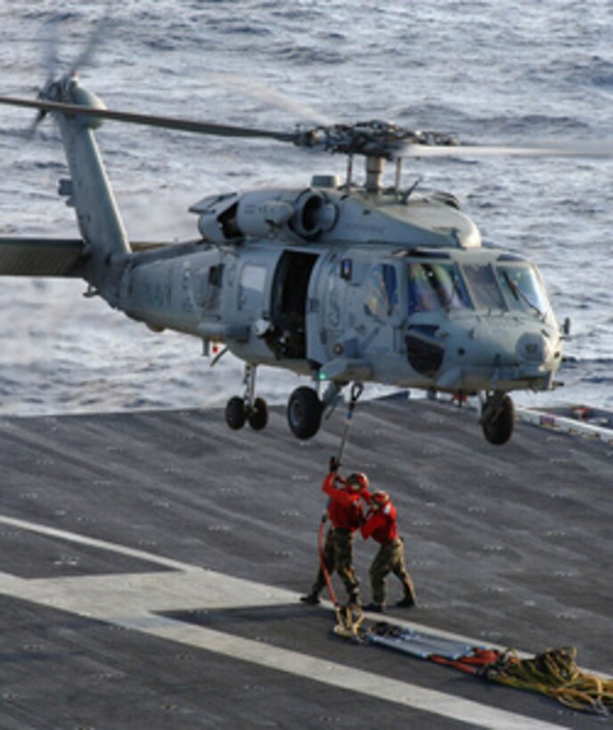Sailors aboard the aircraft carrier USS Enterprise (CVN 65) connect a set of replenishment slings to the cargo hook of an HH-60 Seahawk helicopter during a vertical ammunition on-load conducted with the aircraft carrier USS Harry S. Truman (CVN 75) on Nov. 3, 2005. The Truman is offloading munitions to the Enterprise, USNS Arctic (T-AOE 8), and the USS Dwight D. Eisenhower (CVN 69) as the ships operate in the Atlantic Ocean. 