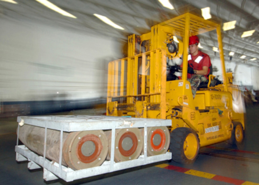 Navy Petty Officer 3rd Class Alexander Jensen moves ordnance through the hangar bay of the aircraft carrier USS Harry S. Truman (CVN 75) on Nov. 3, 2005. The Truman is offloading munitions to the Enterprise, USNS Arctic (T-AOE 8), and the USS Dwight D. Eisenhower (CVN 69) as the ships operate in the Atlantic Ocean. 