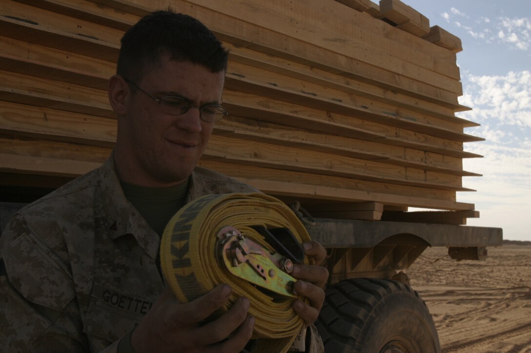 Lance Cpl. Richard C. Goettel, a logistics vehicle system operator assigned to Transportation Support Company, Combat Logistics Battalion 2, 2nd Marine Logistics Group (Forward), rolls a tie-down strap after delivering a load of building supplies to a forward operating base near Husaybah, Iraq. Goettel is a 19-year-old native of Buffalo, N.Y.
