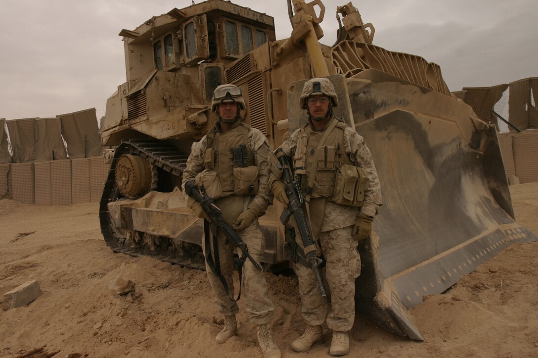 Chief Warrant Officer 4 Alan J. Clyne (left), commanding officer of maintenance detachment, and Master Sgt. Scott E. Witmer, maintenance detachment operations chief, both with Combat Logistics Battalion 2, 2nd Marine Logistics Group (Forward), stand in front of the D9 bulldozer they used to clear a path to safety to stranded Marines during Operation Steel Curtain.
