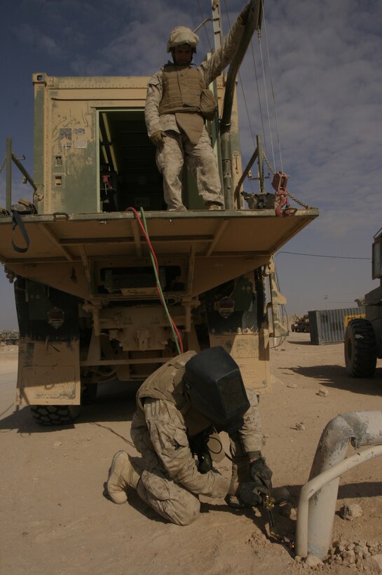 Sgt. Michael L. Dukes (top), an amphibious assault vehicle mechanic and native of Bedford, Iowa, and Sgt. James E. Owens, an artillery mechanic and native of West Union, W.V., use their unit?s modified MK-23 short-bed 7-ton truck to make improvements around Camp Gannon. Both are assigned to Combat Logistics Battalion-2, 2nd Marine Logistics Group (Forward).